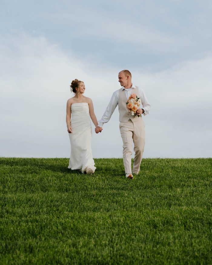 Couple walking hand in hand across an open field